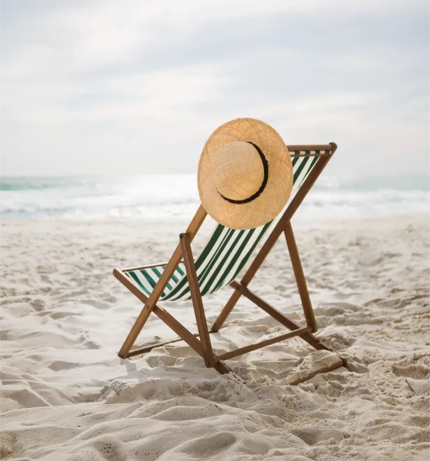 Beach chair with a straw hat on white sand near the sea